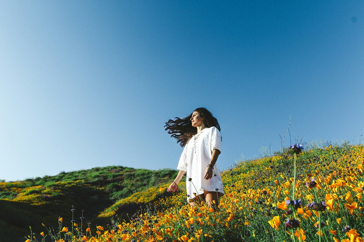 smiling woman in a white dress, standing in a meadow